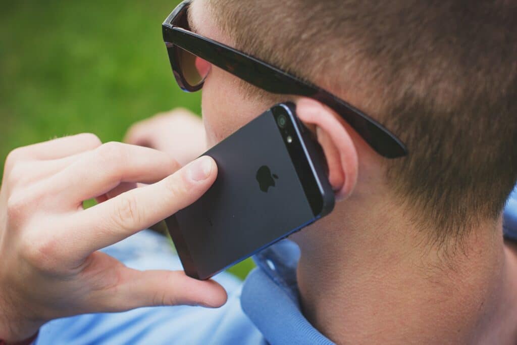 Man Putting His Black Iphone 5 on His Left Ear
