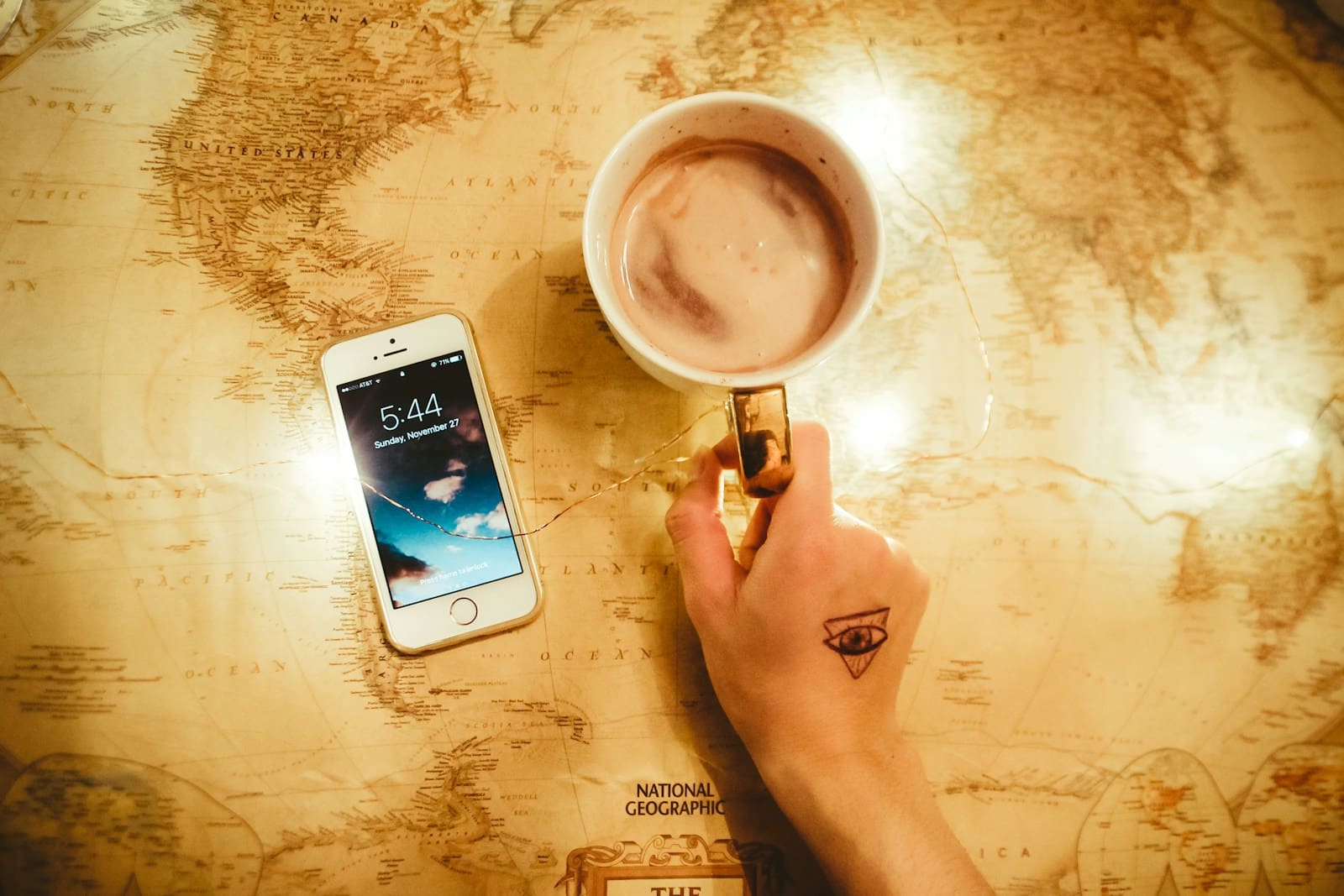 person holding mug beside iPhone 5s