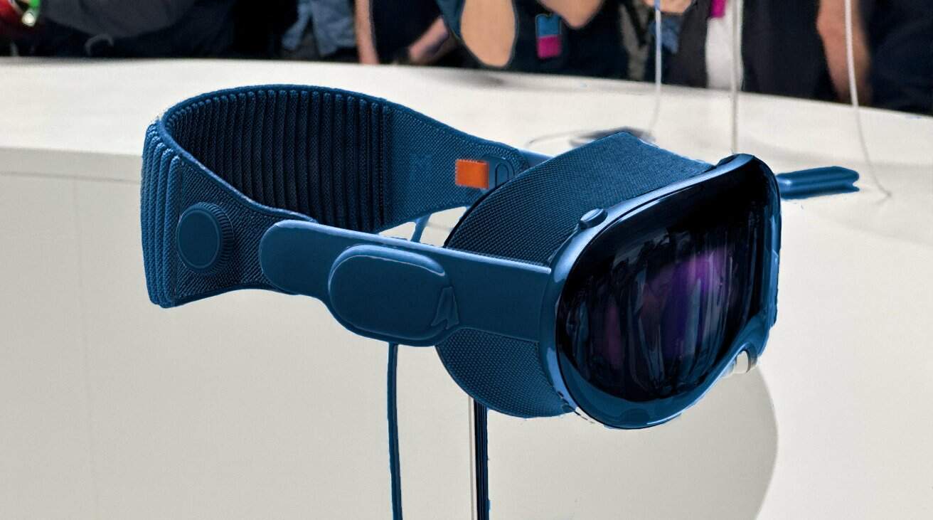 Blue virtual reality headset with reflective lens and adjustable fabric strap, placed on a minimalist white display stand.
