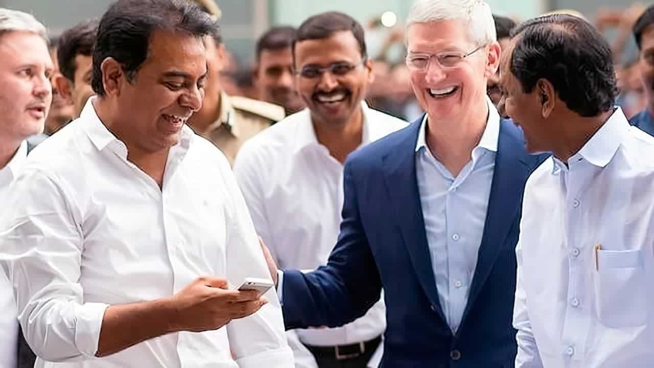 Group of men laughing and smiling together, with one holding a smartphone, while wearing business and casual attire in a lively setting.