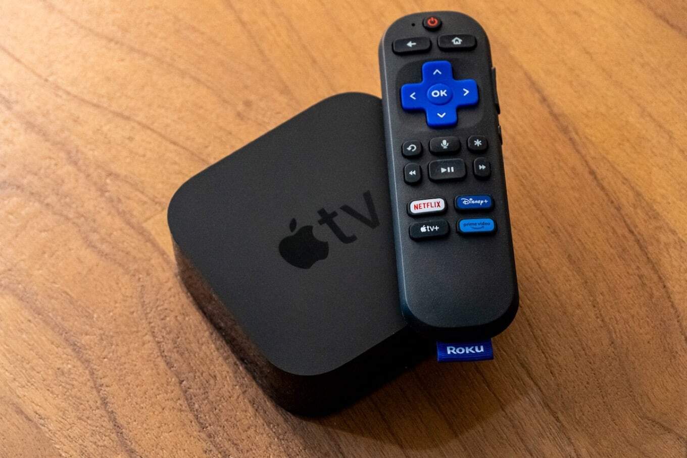 A photo of an Apple TV box with a Roku voice remote on top of it showing the Apple TV+ promotional button.
