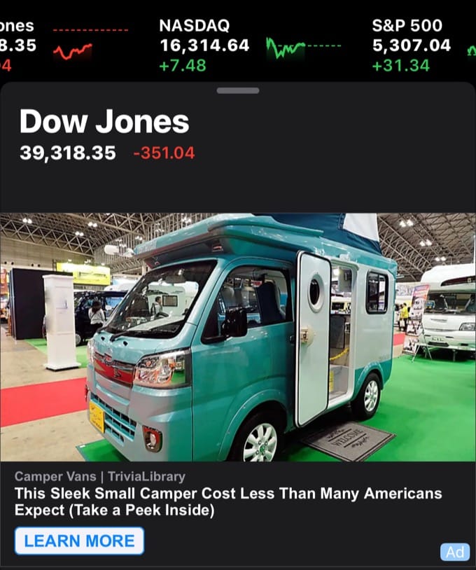A screenshot of the iOS Stocks app showing the stock ticker at the top, and the Dow Jones section of the Stocks news, with ads. The ad is for 'Camper Vans | TriviaLibrary. This Sleek Small Camper Cost Lesss Than Many Americans Expect (Take a Peek Inside)