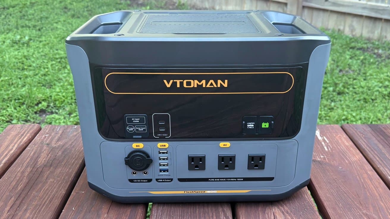 A portable power station sits on a wooden surface, featuring multiple outlets, including DC, USB, and AC ports, with a digital display for power management.
