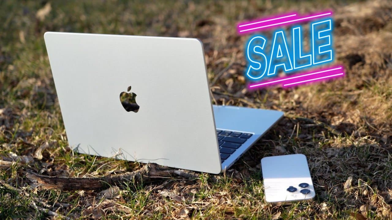 Open MacBook Air laptop and iPhone on grass, with neon blue and pink 'Sale' text above them.