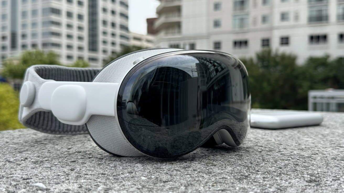 VR headset with reflective lens and fabric strap on a concrete surface, against a blurred urban backdrop with buildings and greenery.