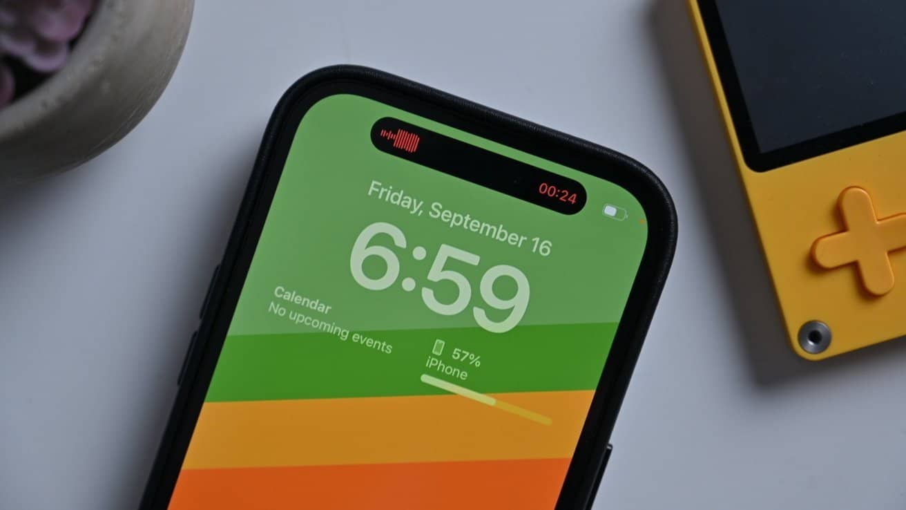 Smartphone displaying time 6:59, calendar with no events, battery at 57%, alongside a yellow handheld gaming device on a white surface.