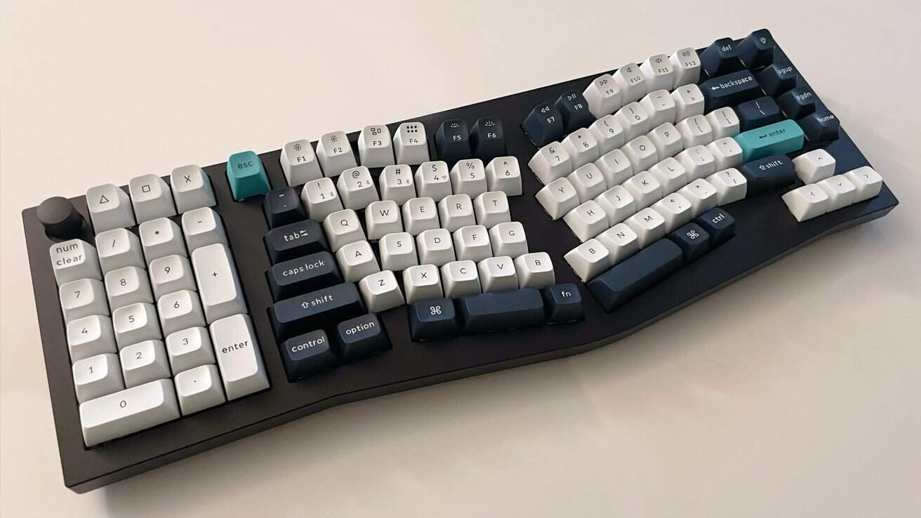 Ergonomic keyboard with white and dark blue keys on a curved layout, featuring teal escape and enter keys, a number pad, and a black base.