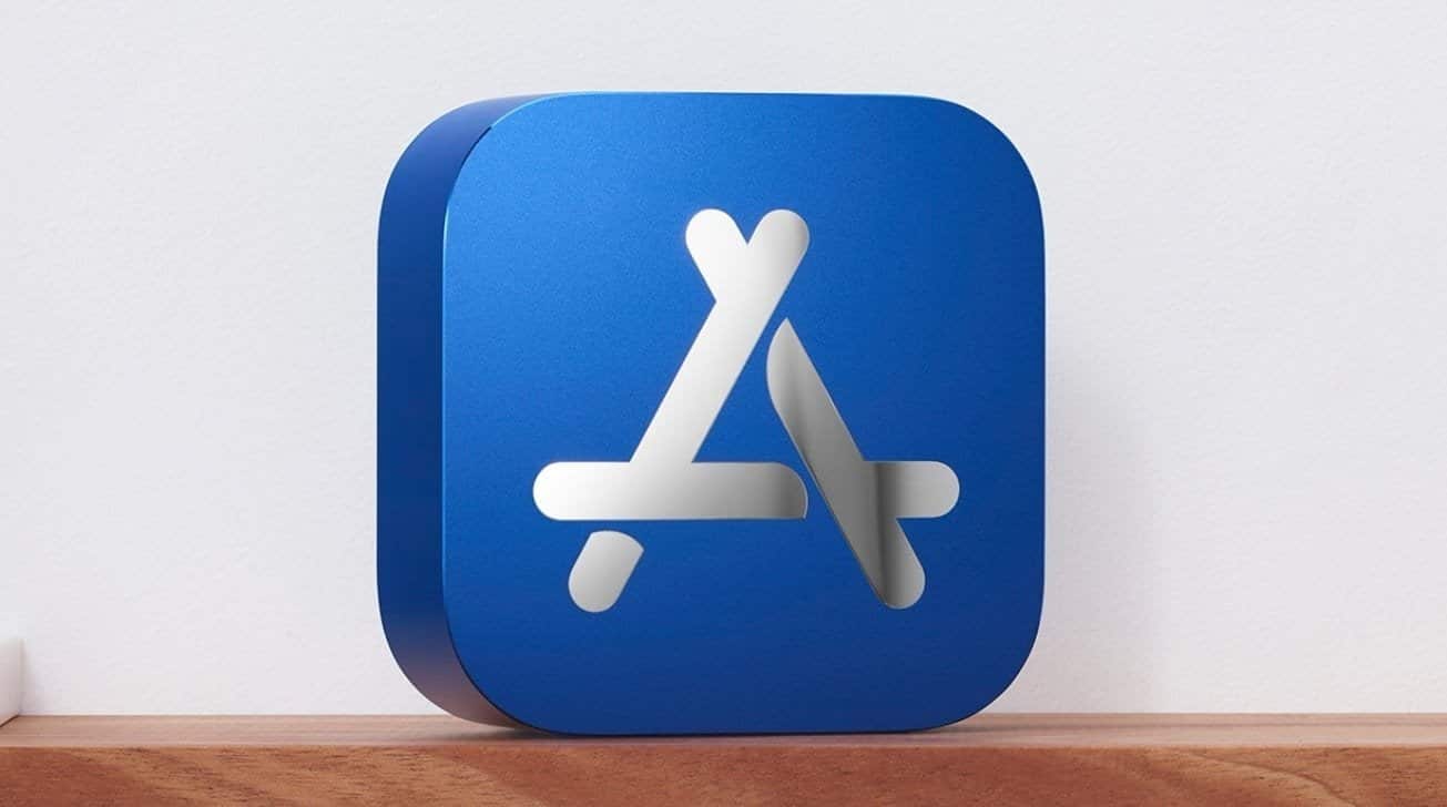 Blue block with a raised Apple App Store logo featuring stylized tools, placed on a wooden surface near a white wall.