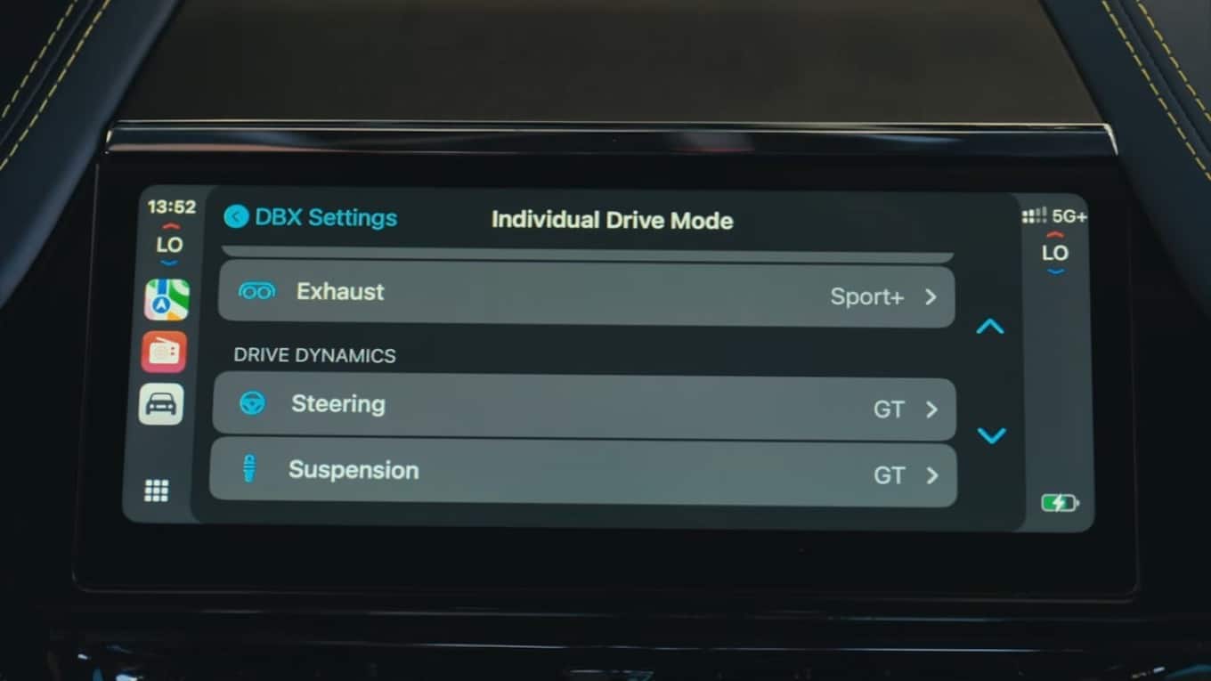 A screengrab from the Top Gear video on Aston Martin's implementation of CarPlay. The camera shows us the center console displaying vehicle settings on the short, but wide screen. Labels for the settings are aligned to the left side of the screen, and the current setting is aligned to the right side of the screen with a large gap between them. Also, everything is gray on gray with narrow text.