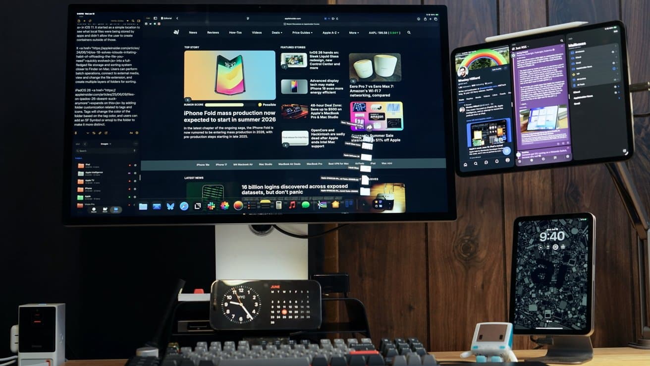 Desk setup with mounted monitors displaying tech content, digital clock, keyboard, smartphone, and tablet, all against a wooden wall backdrop.