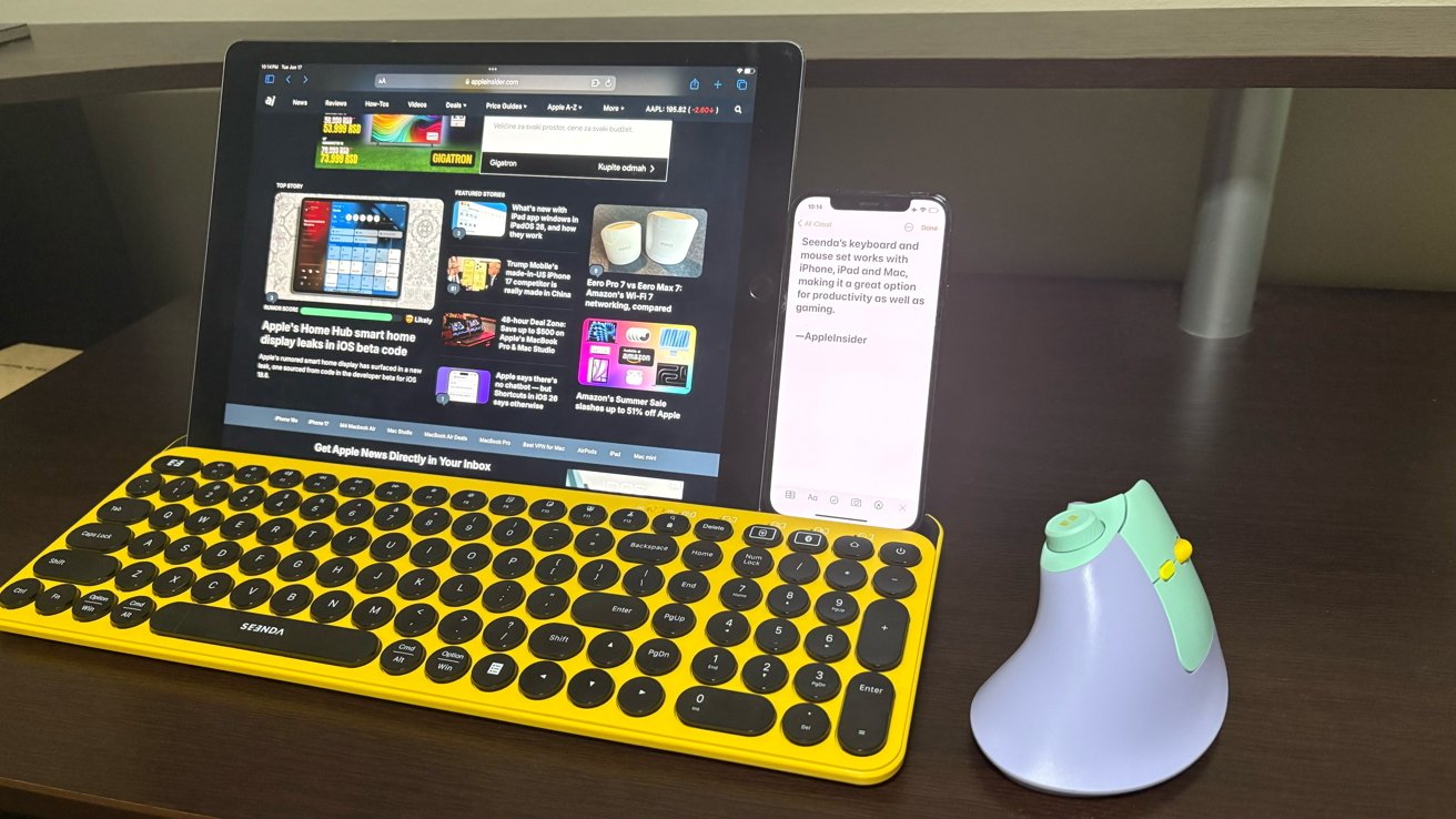 Tablet with news website, smartphone with text, yellow and black keyboard, ergonomic mouse on dark wooden desk.