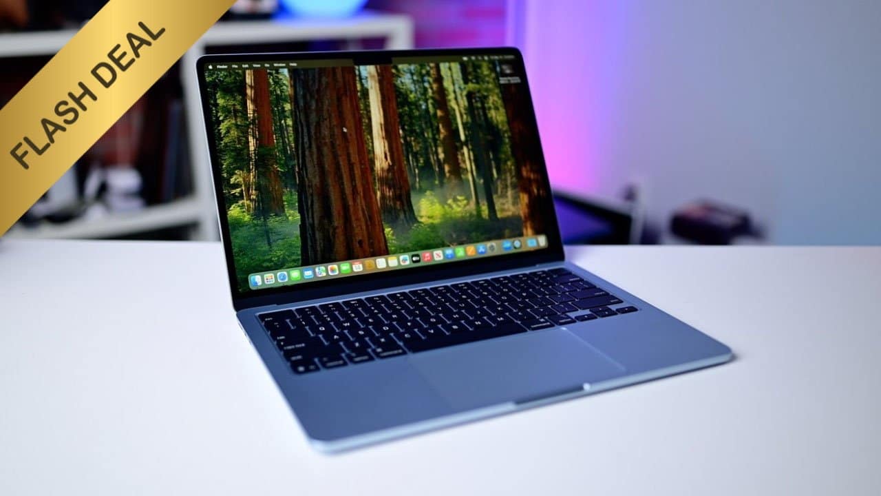 Open M4 MacBook Air on white table with forest wallpaper on screen, flash deal banner on top left corner.