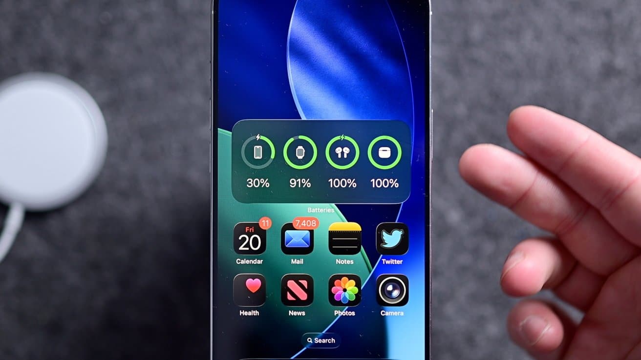 Smartphone screen displaying battery widget percentages, including 30% and 91%, with various app icons like Calendar, Mail, Notes, and Twitter. Person's hand partially visible.