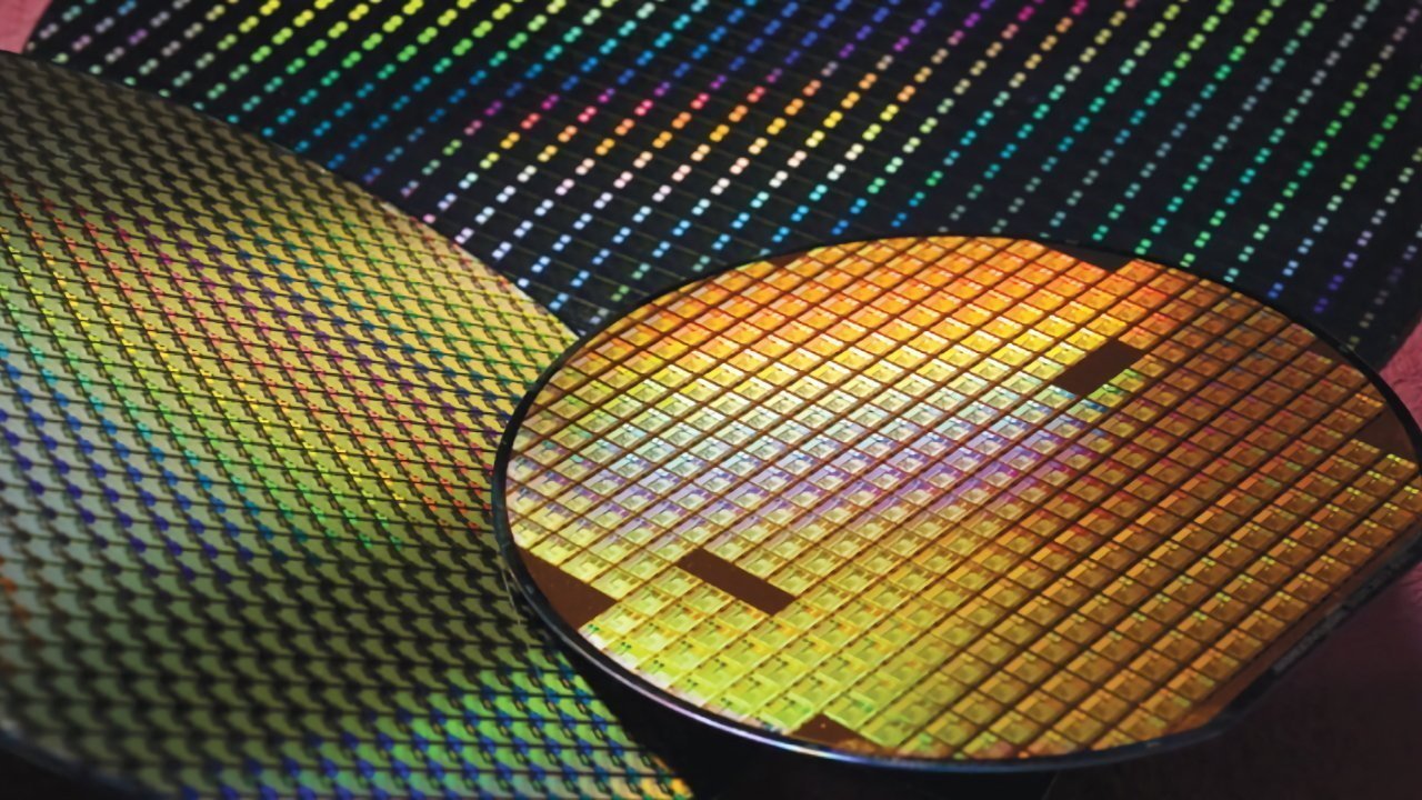 Colorful silicon wafers with intricate grid patterns reflecting light.