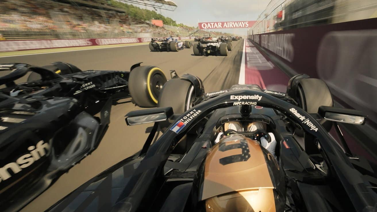 Formula 1 cars racing on a track, with a close-up of one car in the foreground, crowd and Qatar Airways banner in the background.
