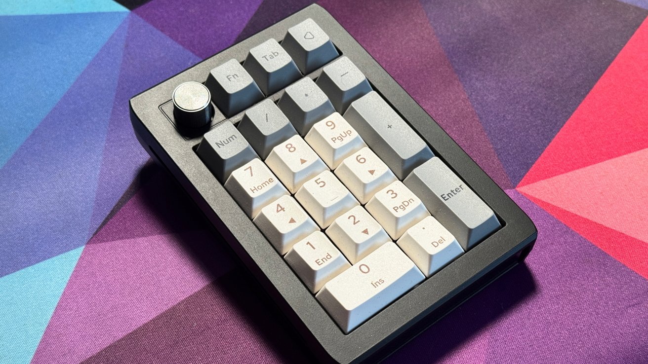 A numeric keypad with a silver knob rests on a colorful geometric-patterned surface.