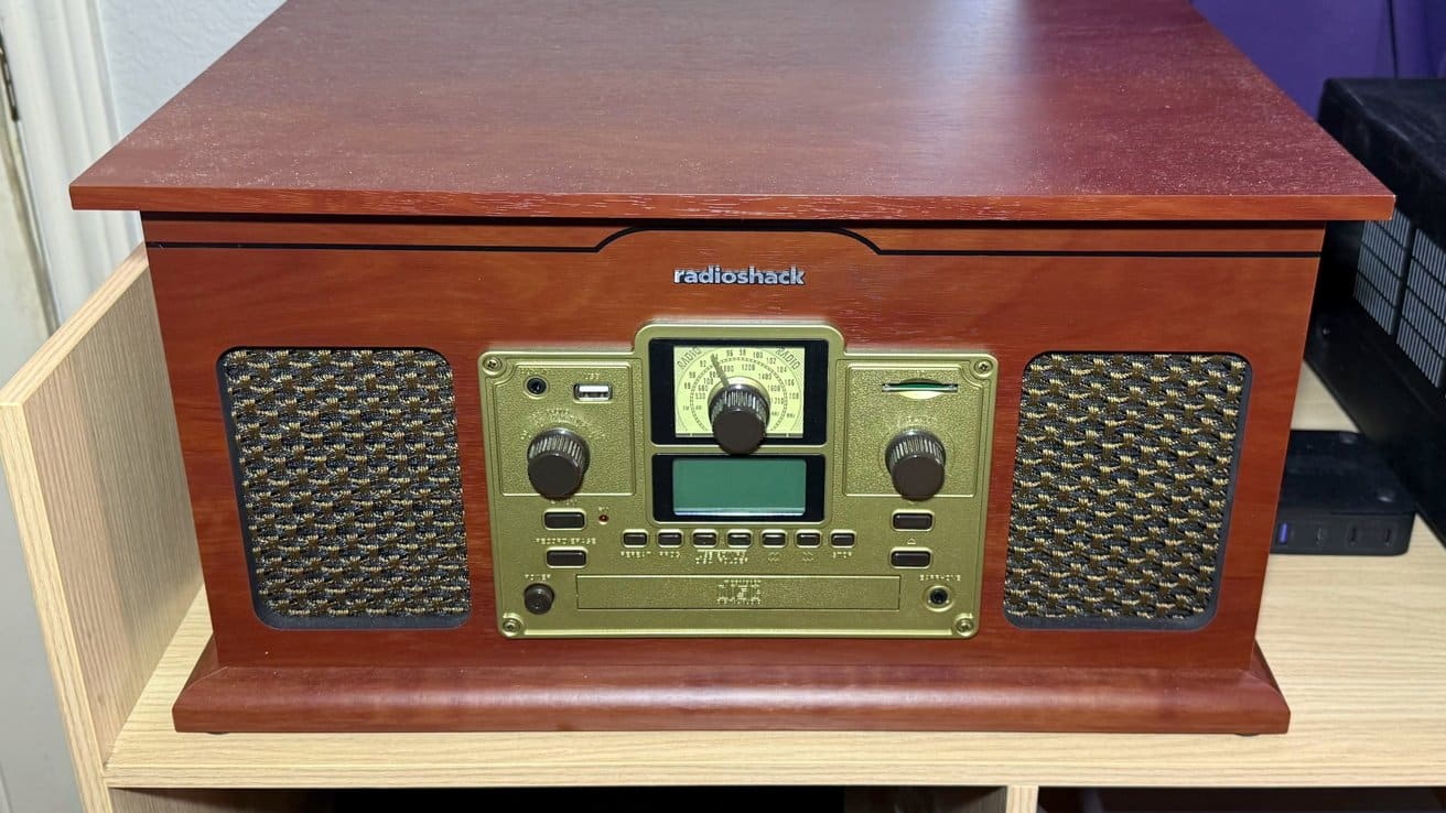 Wooden vintage-style radio with mesh speaker covers, gold-tone control panel, dials, and RadioShack logo on top, placed on a light wood shelf.
