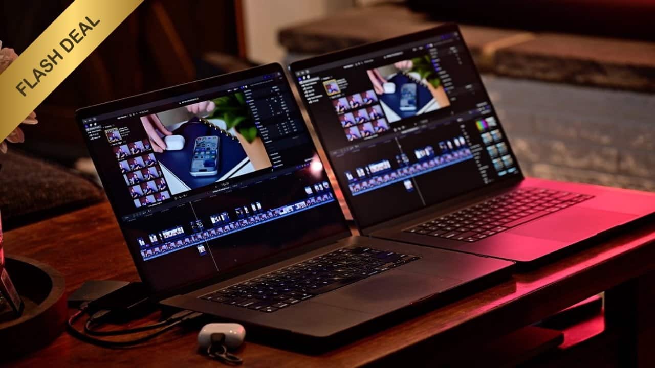 Two 16-inch MacBook laptops displaying video editing software on a wooden table, with a small device and cable beside them, and a 'Flash Deal' label in the corner.