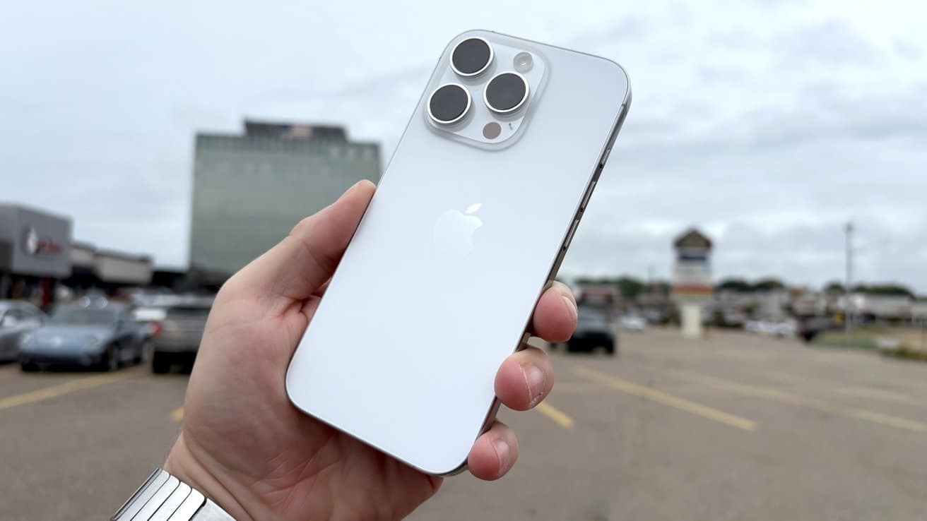 The white titanium iPhone 16 Pro showing the back to the camera while outside