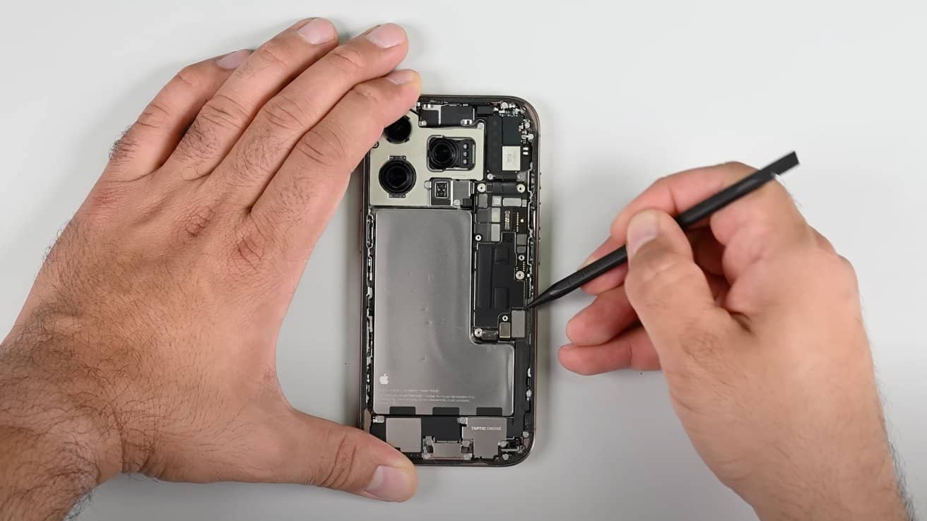 Hands repairing the inside of a mobile phone with a tool on a white background.