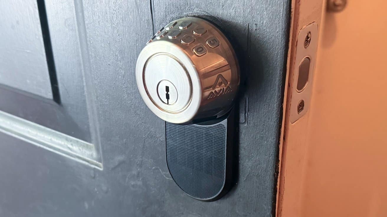 Smart lock with a circular design on a dark door, showing a keypad and keyhole. Orange interior wall visible on the right side.