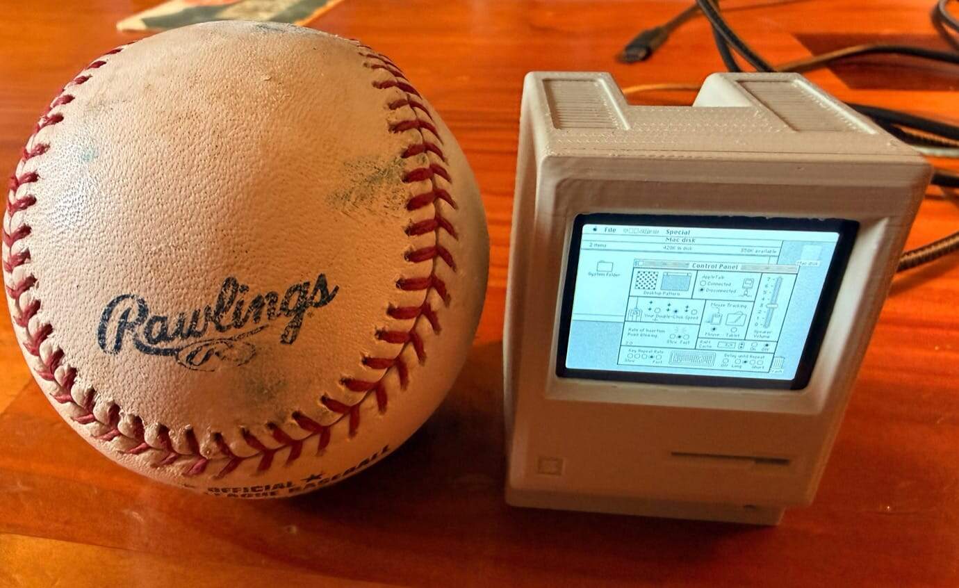 A Rawlings baseball next to a vintage computer with a screen displaying a software interface.